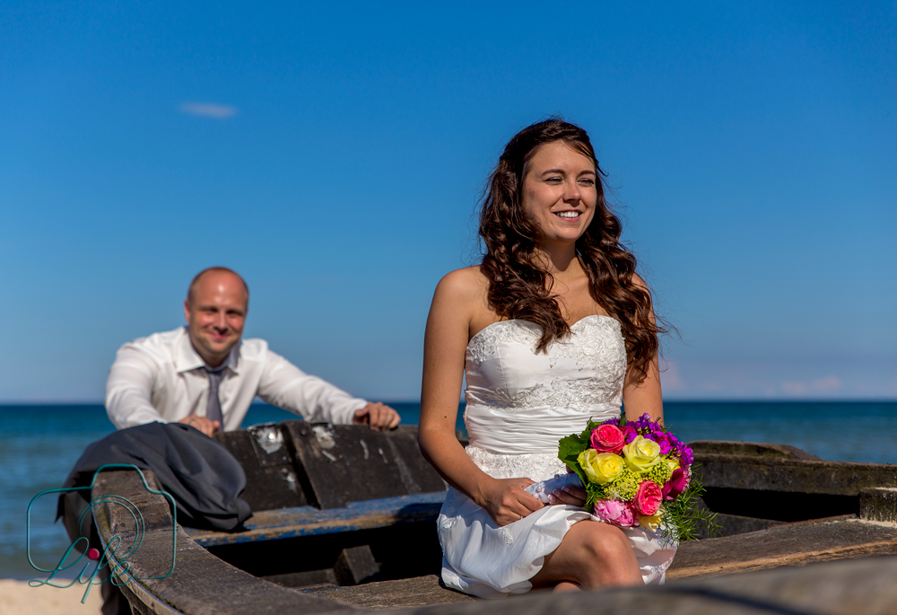 Foto eines Hochzeitspaares: Brautpaar am Strand mit Boot