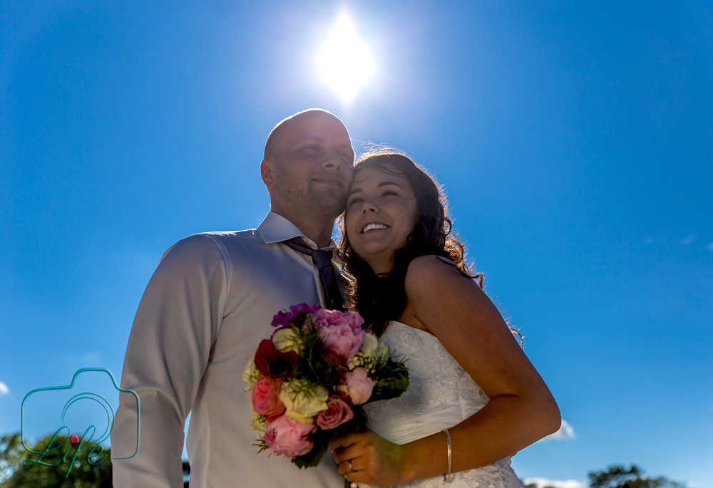 Foto eines Hochzeitspaares: Brautpaar mit Sonne im Hintergrund