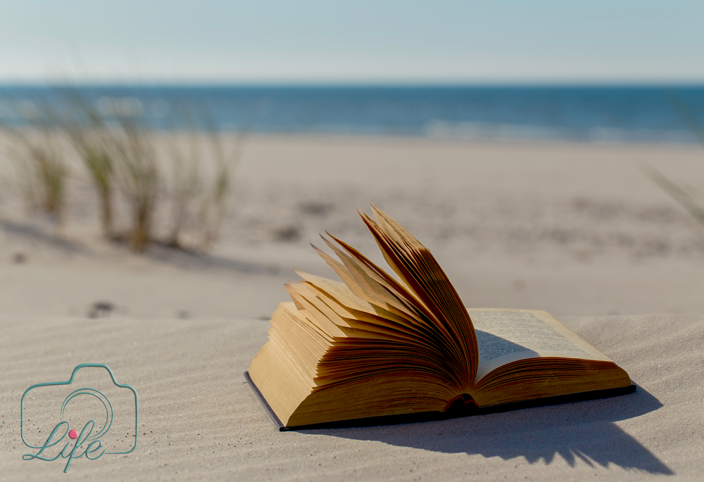 Werbe-Foto: Buch im Sand am Strand mit Meer im Hintergrund
